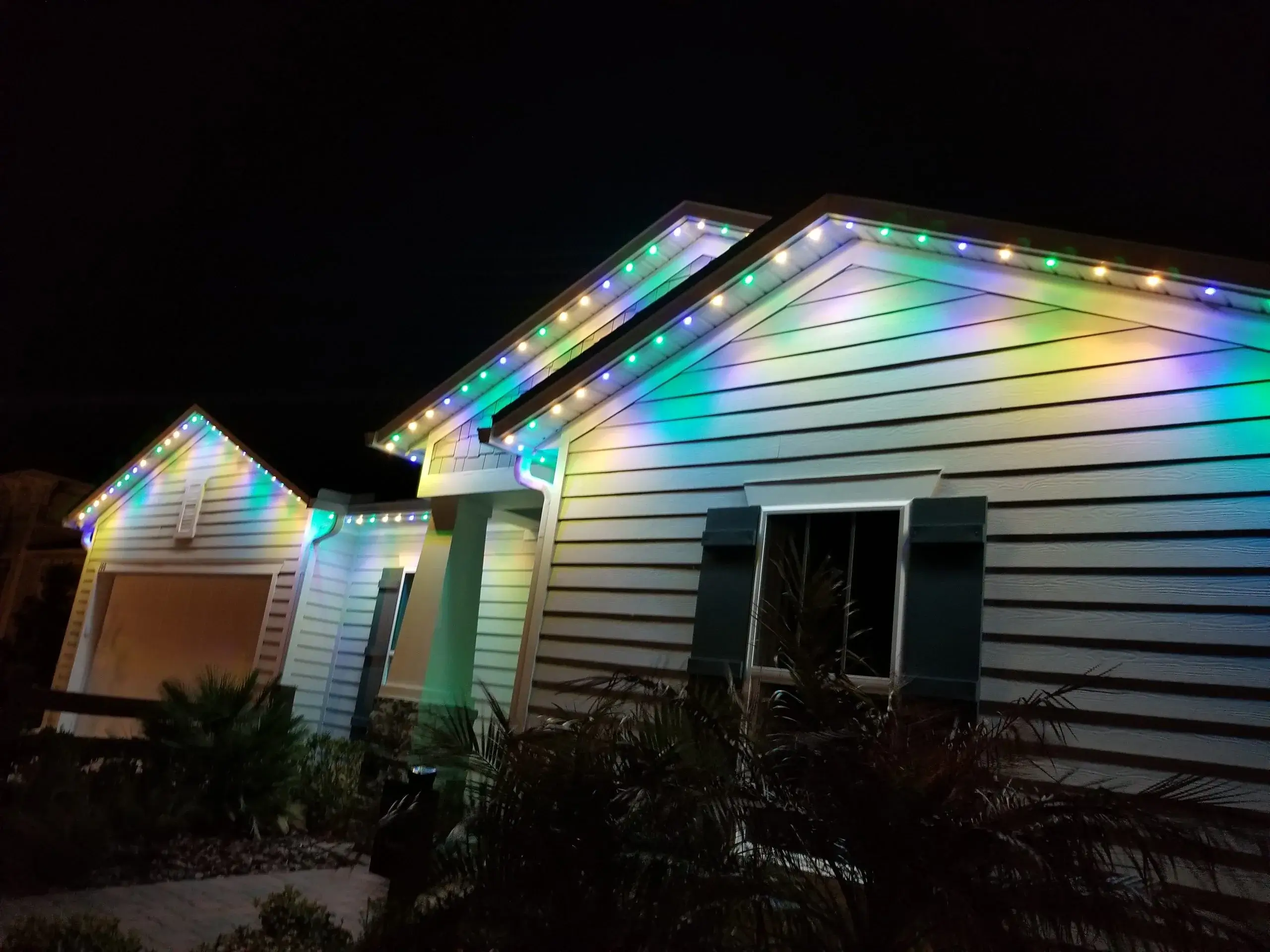 Colorful lights illuminate a house against a dark night sky
