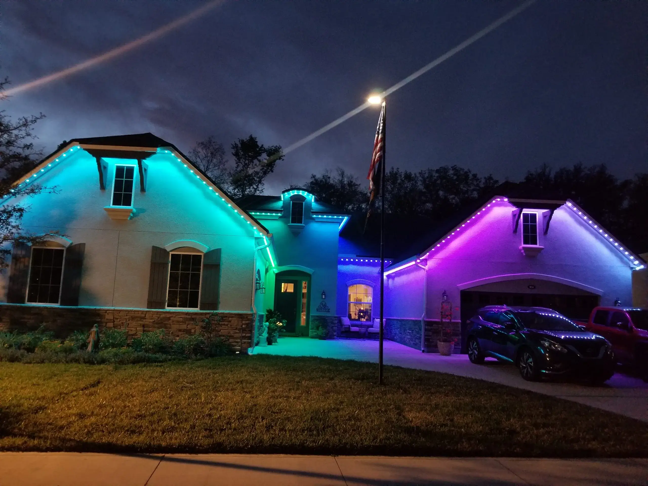 Exterior lighting experts showcase vibrant blue and purple lights illuminating a house at night