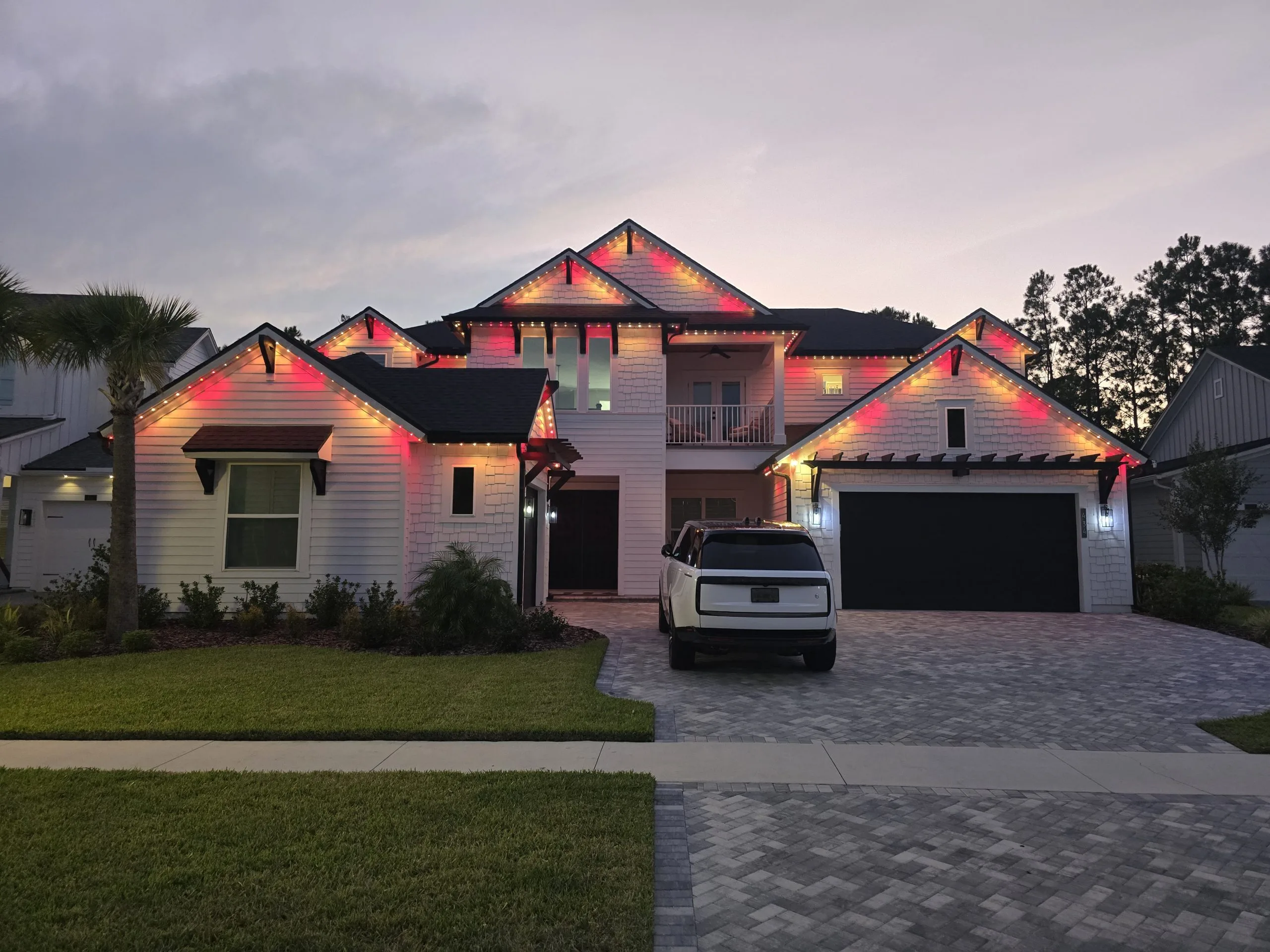 Landscape lighting Jacksonville enhances a modern house with colorful lights at twilight