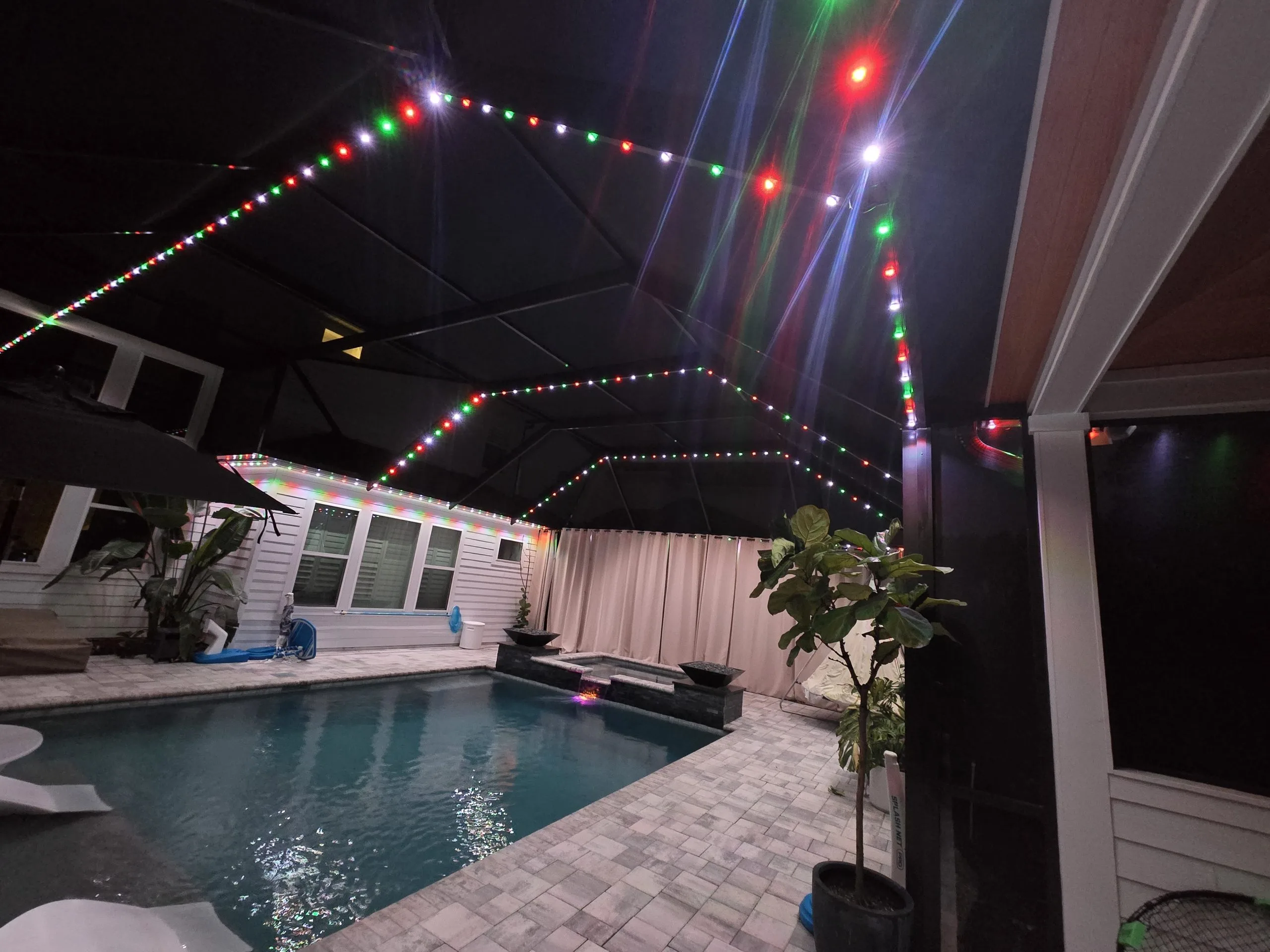 String lights illuminate a cozy pool area under a canopy