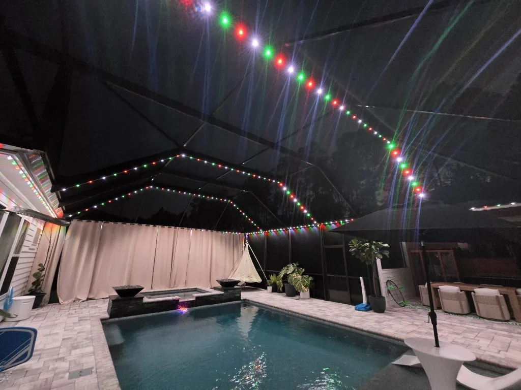 Pool cage lighting enhances the ambiance with colorful string lights under a dark sky