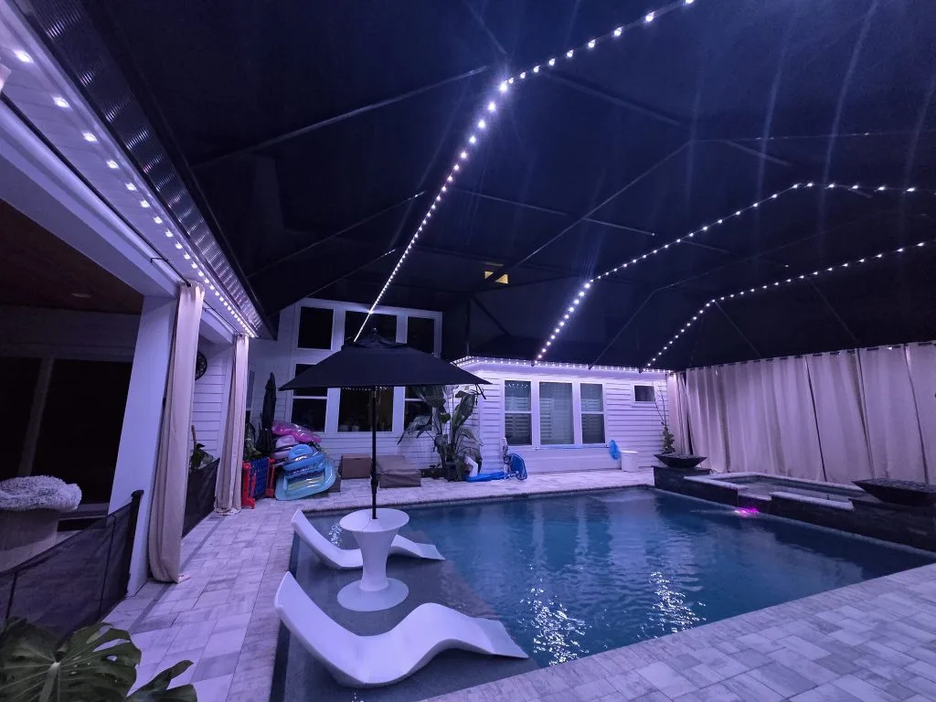 Pool cage lighting softly illuminates a tranquil pool area under a dark canopy