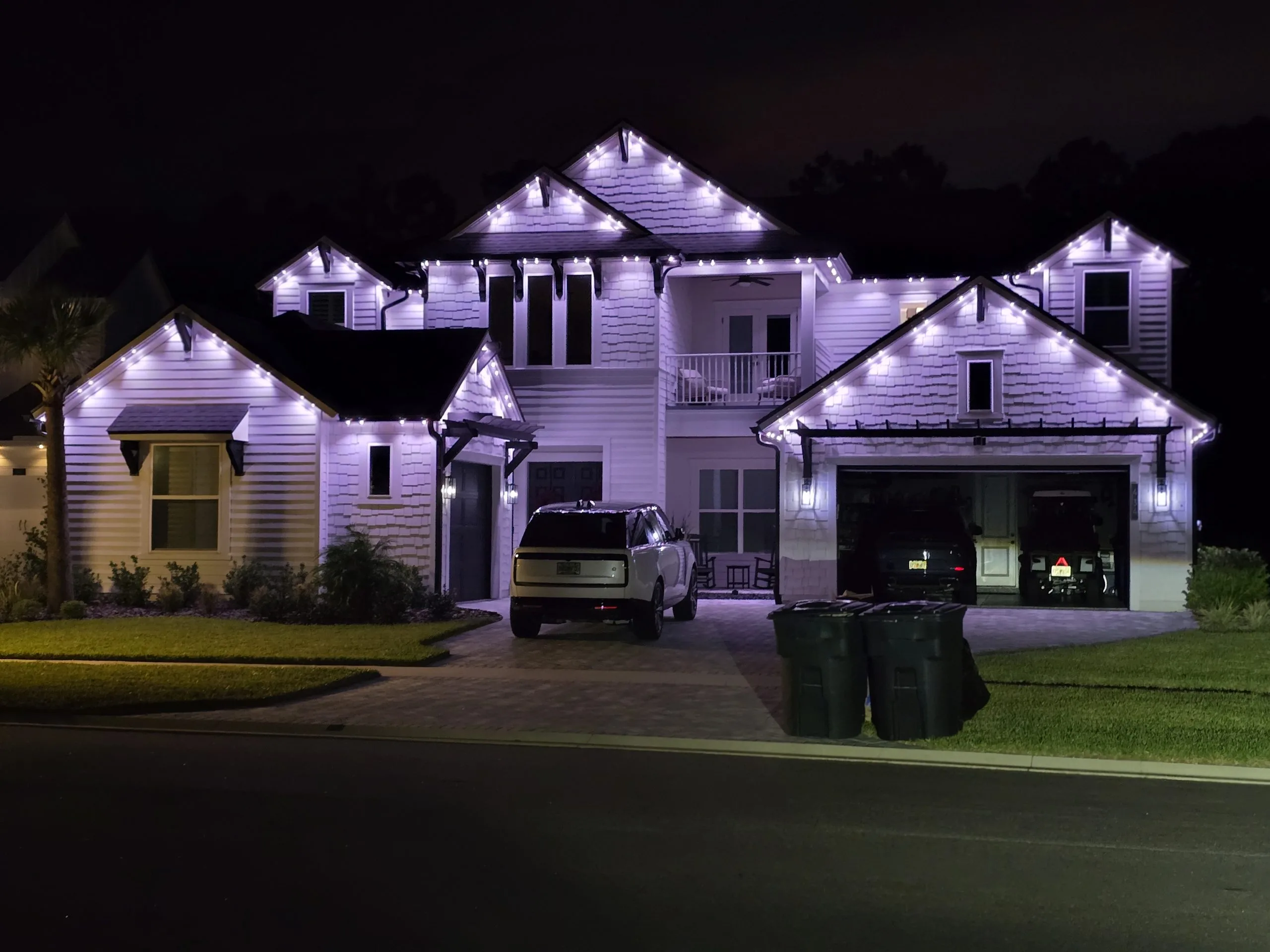 Architectural lighting illuminates a house with vibrant purple lights at night