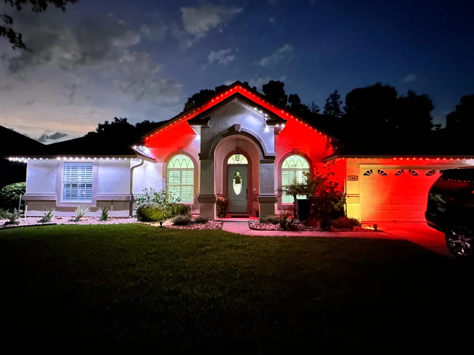 A beautifully lit house at dusk showcases colorful lights and a welcoming entrance
