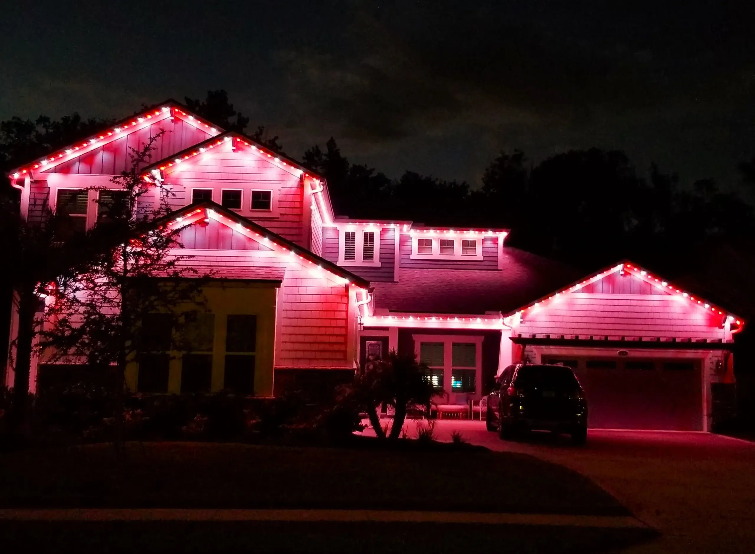 Holiday lighting Jacksonville showcases a house adorned with vibrant pink lights at night