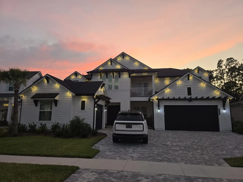 A beautifully lit modern house stands against a colorful sunset sky