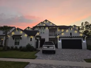 A beautifully lit modern house stands against a colorful sunset sky