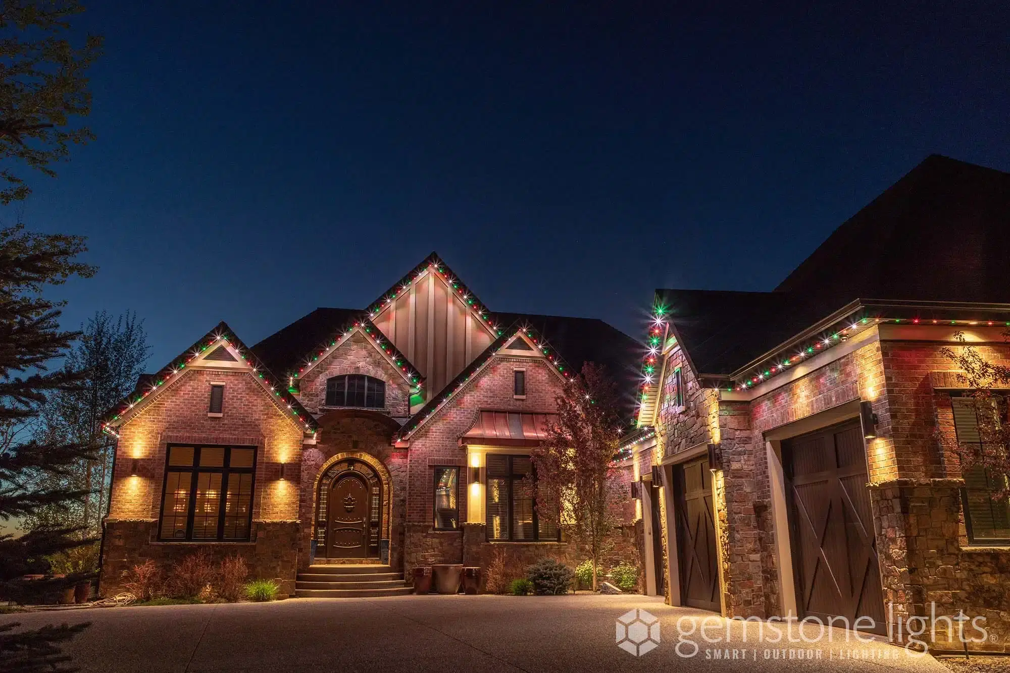 A beautifully decorated home is illuminated with colorful lights against a twilight sky