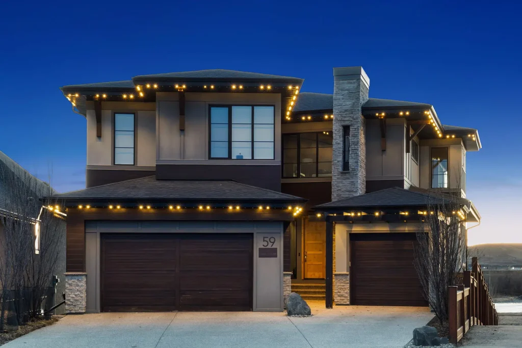 A modern house is beautifully illuminated with string lights at dusk