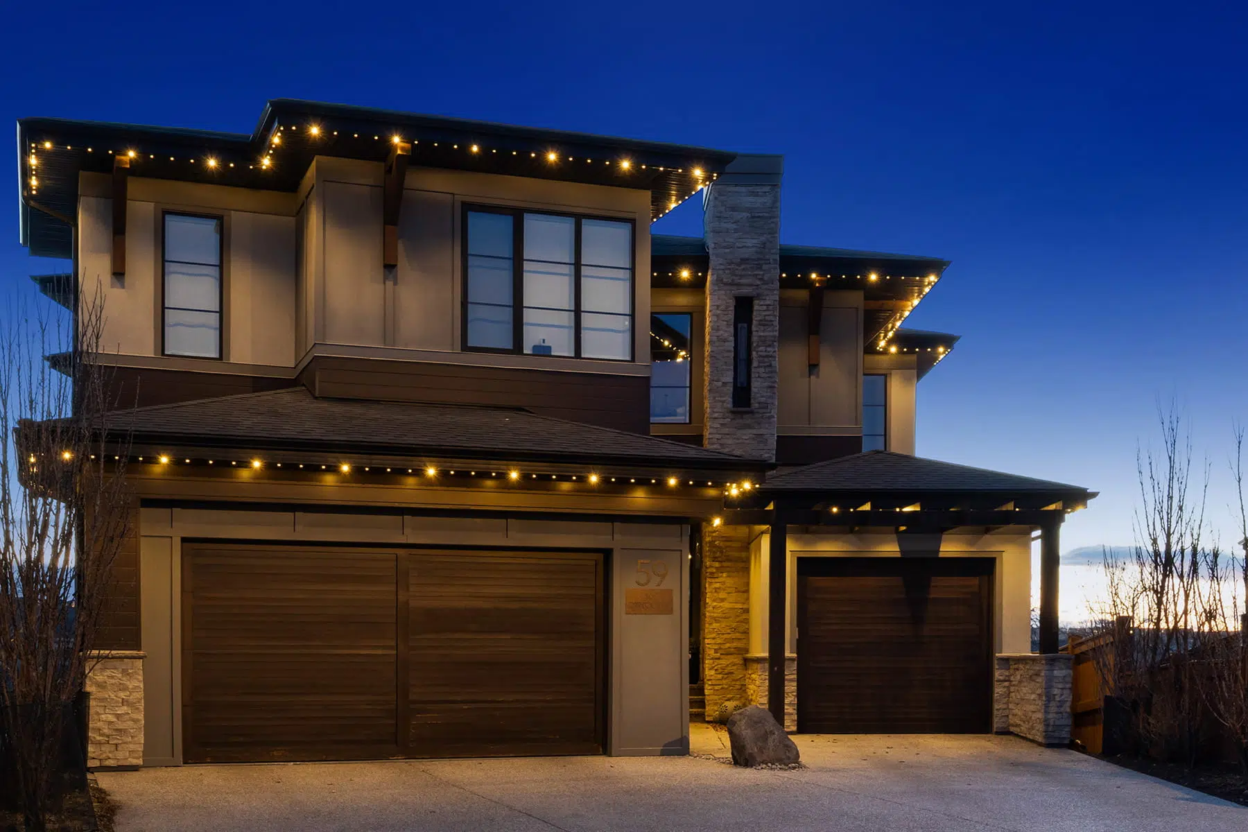 A modern house adorned with warm, glowing lights against a twilight sky