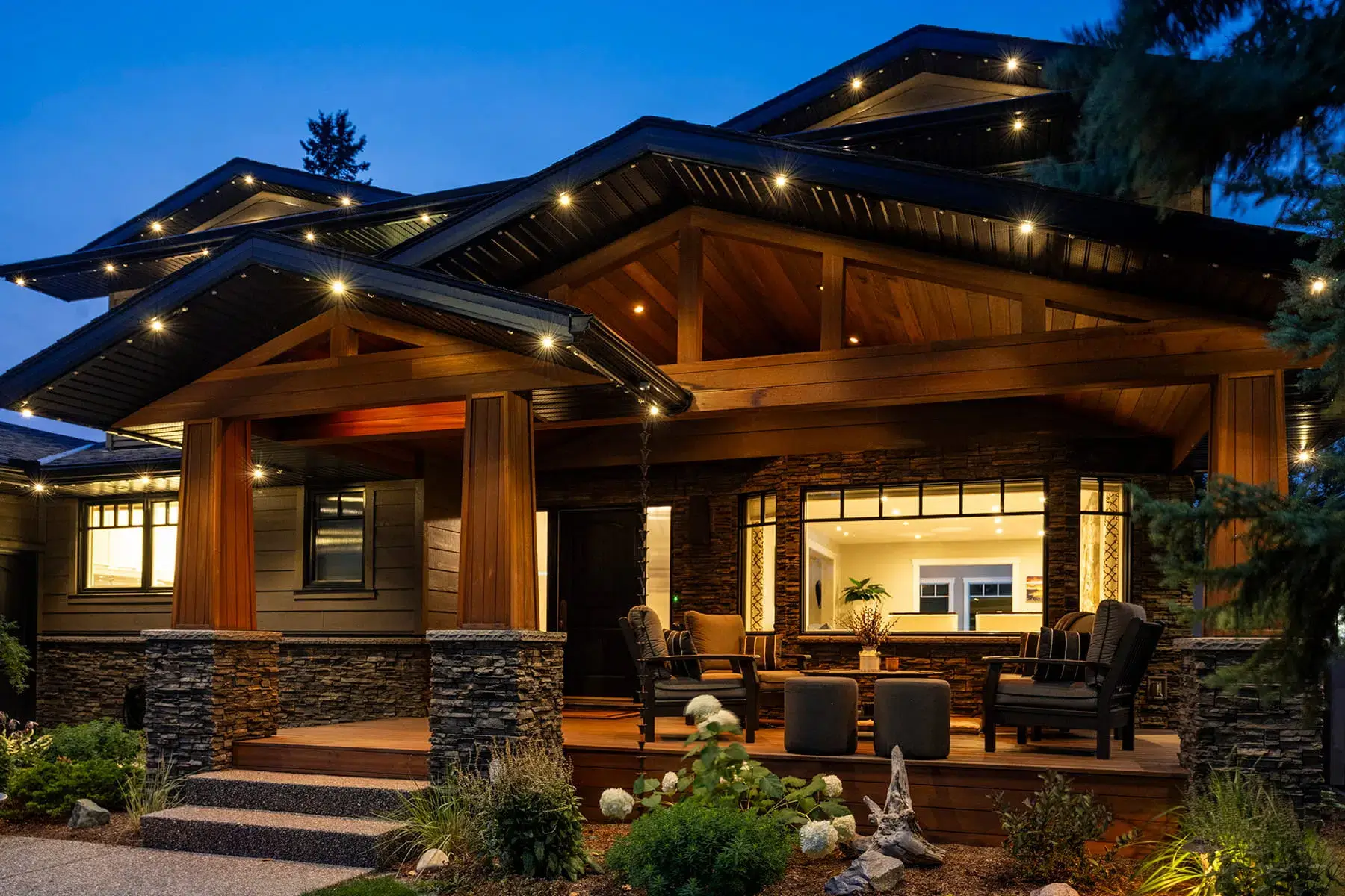 A beautifully illuminated house features a welcoming porch with cozy seating